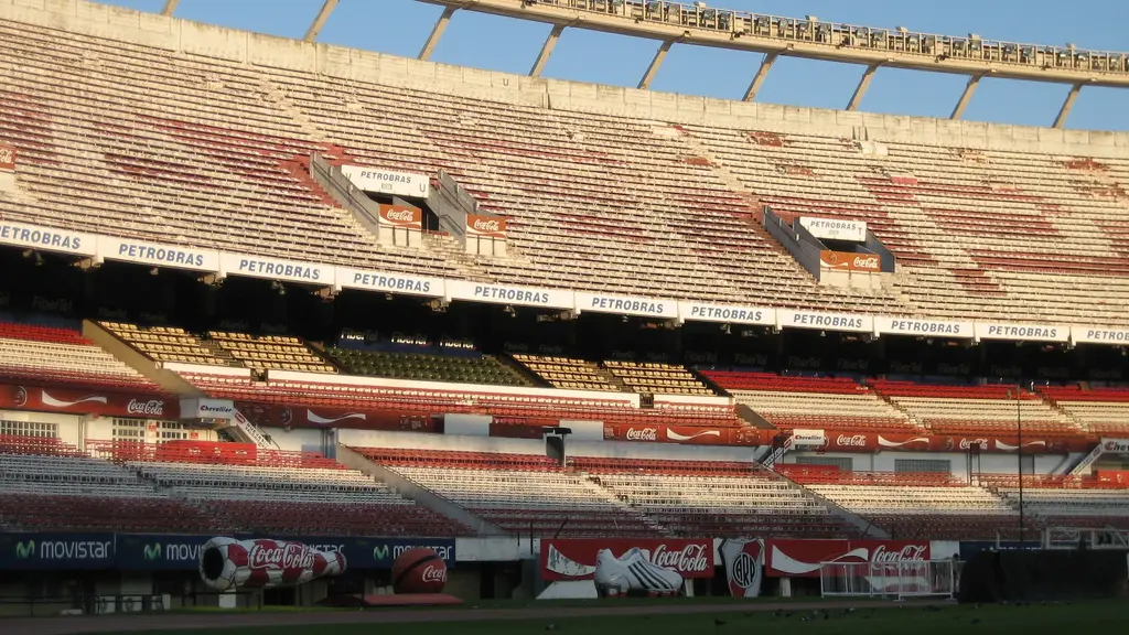 Tribunas vacías del Estadio Monumental de River Plate, en Buenos Aires, iluminadas por la luz del atardecer, con butacas rojas y blancas. Foto: Stefano Vigorelli / Wikimedia Commons (CC BY-SA 4.0) (archivo)