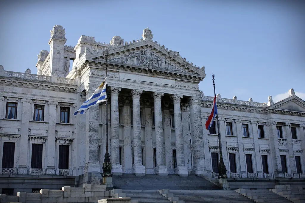 Fachada del Palacio Legislativo con la bandera uruguaya flameando frente a la escalinata principal. Foto: Cinthya Novas / Wikimedia Commons (CC BY-SA 3.0) (archivo)