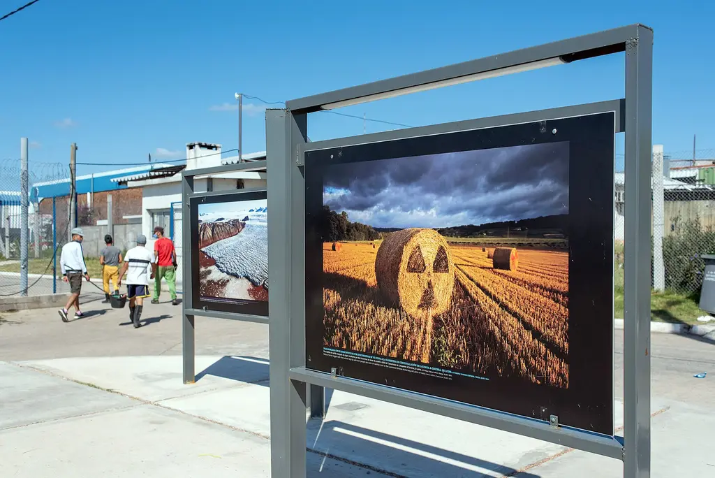 Internos caminan junto a una muestra fotográfica en la Unidad 4 de Santiago Vázquez, ex Comcar. Foto: Ricardo Antúnez / Centro de Fotografía de Montevideo / Wikimedia Commons (CC BY-SA 4.0) (archivo)