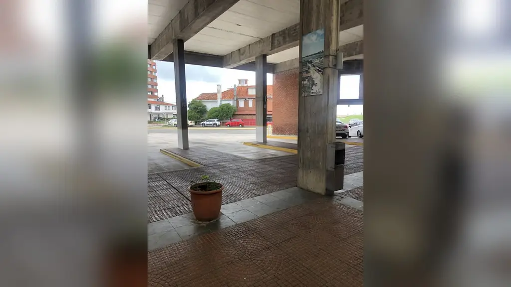 Andén techado de la terminal de ómnibus de Punta del Este, con columnas de hormigón y autos estacionados en la calle. Foto: JacobinoWunsh / Wikimedia Commons (CC BY-SA 4.0) (archivo)