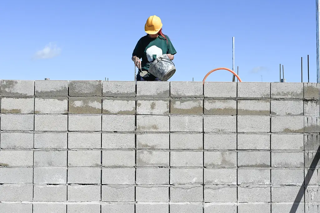 Una trabajadora levanta un muro de bloques en obras de mejora barrial en Los Milagros, Montevideo. Foto: Pablo La Rosa / Wikimedia Commons (CC BY-SA 4.0) (archivo)