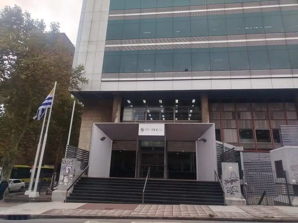 Fachada de la sede de la Dirección General Impositiva en Montevideo, con la bandera uruguaya en la entrada. Foto: BiblioJu / Wikimedia Commons (CC BY-SA 4.0) (archivo)