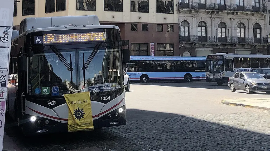 Ómnibus eléctrico con una bandera del Día del Patrimonio en el frente, estacionado junto a la Puerta de la Ciudadela, en Ciudad Vieja. Foto: JacobinoWunsh / Wikimedia Commons (CC BY-SA 4.0) (archivo)