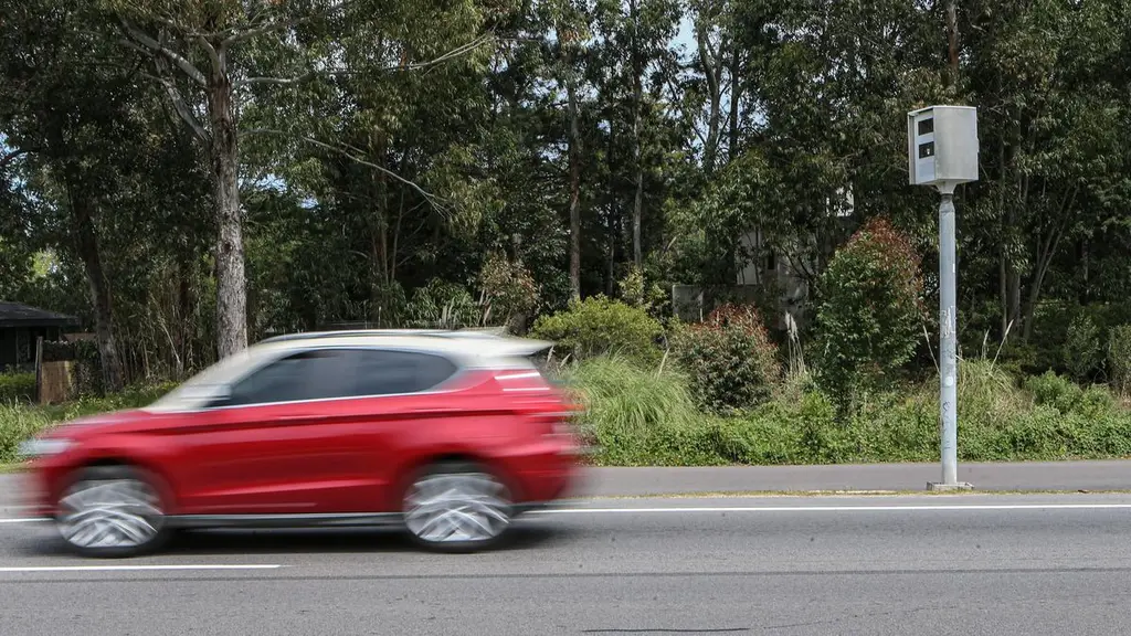 Un auto rojo pasa junto a un radar de velocidad montado en un poste. Foto: El Observador