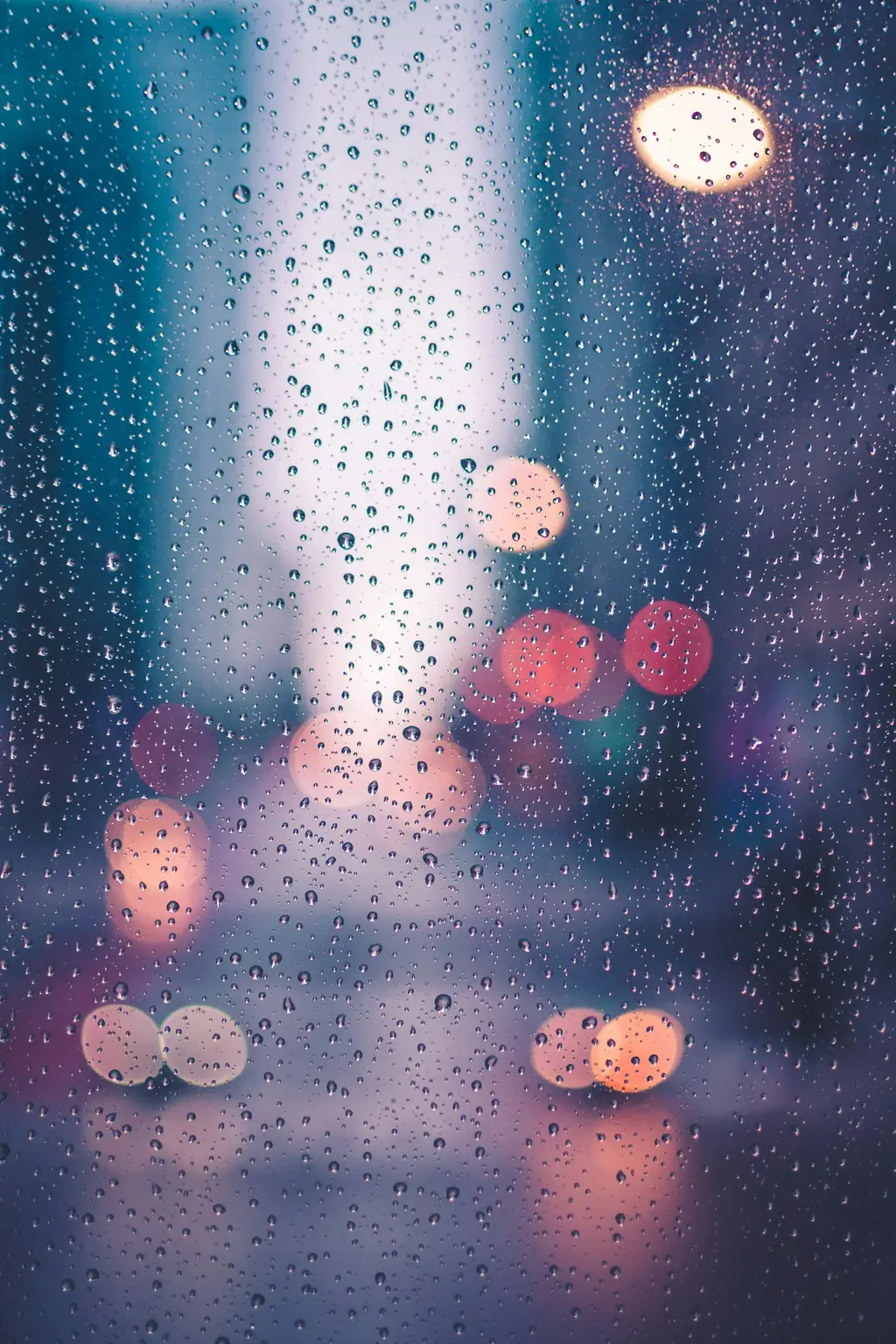 Gotas de lluvia sobre un vidrio, con luces detrás. Foto: Unsplash