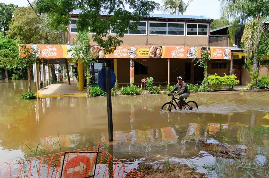 Un hombre pedalea en el agua frente a un local de comidas, en una calle inundada de Paso de la Patria. Foto: La Nación