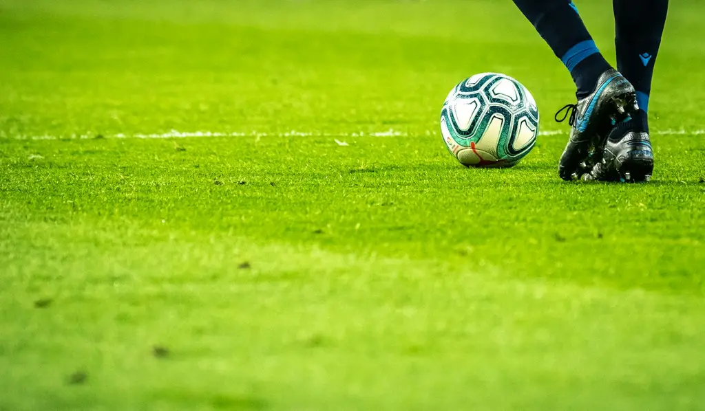 Partido de fútbol bajo luces de estadio. Foto: Unsplash
