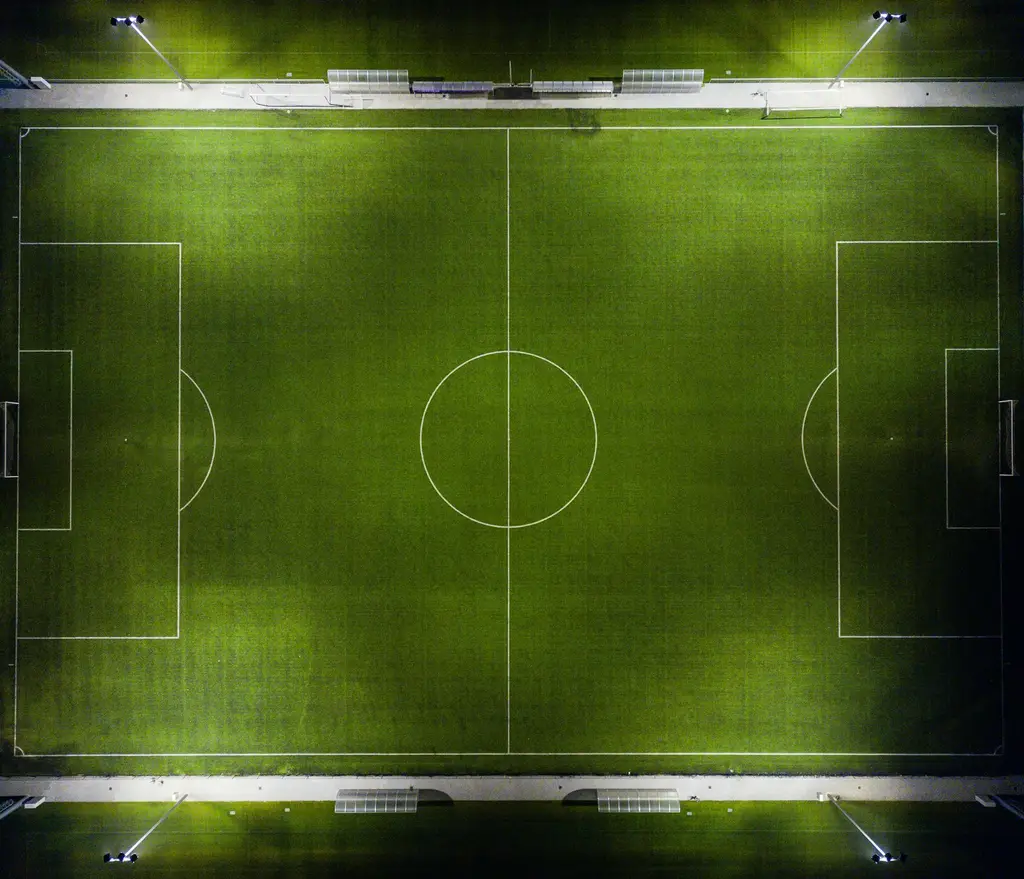 Cancha de fútbol vista desde arriba, iluminada de noche. Foto: Unsplash
