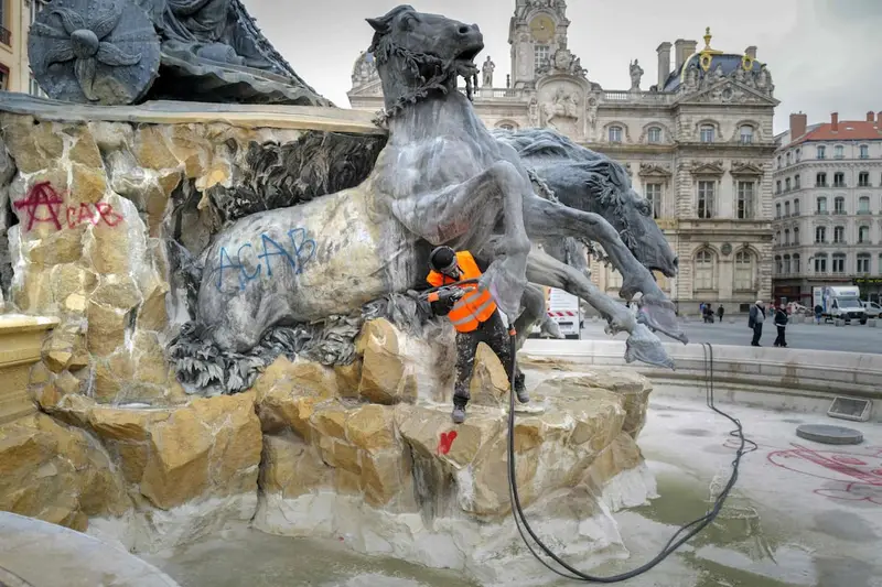 Un operario limpia pintadas en una fuente tras los disturbios en Francia. Foto: La Nación