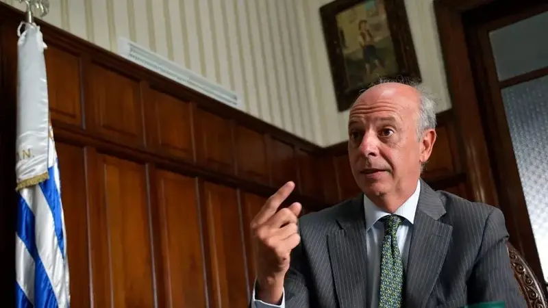 Javier García, de traje gris, habla en un despacho con la bandera uruguaya al lado. Foto: El Observador