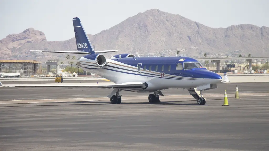Un jet ejecutivo Gulfstream G100 azul y blanco estacionado en la plataforma de un aeropuerto, con montañas al fondo. Foto: Hayden Soloviev / Wikimedia Commons (CC BY-SA 4.0) (archivo)