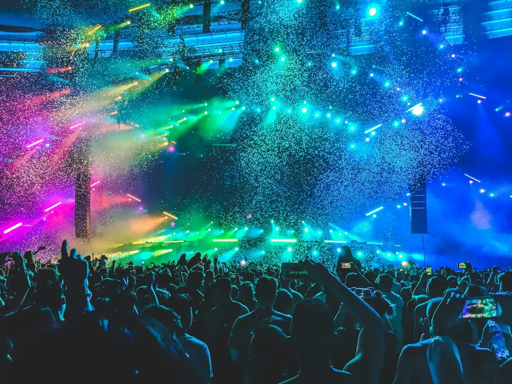 Luces de un recital, de noche, con el público de espaldas. Foto: Unsplash