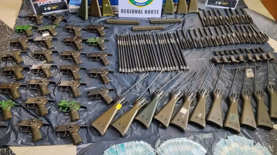 Piezas de fusiles y fajos de dinero exhibidos tras un operativo en Rivera. Foto: Subrayado