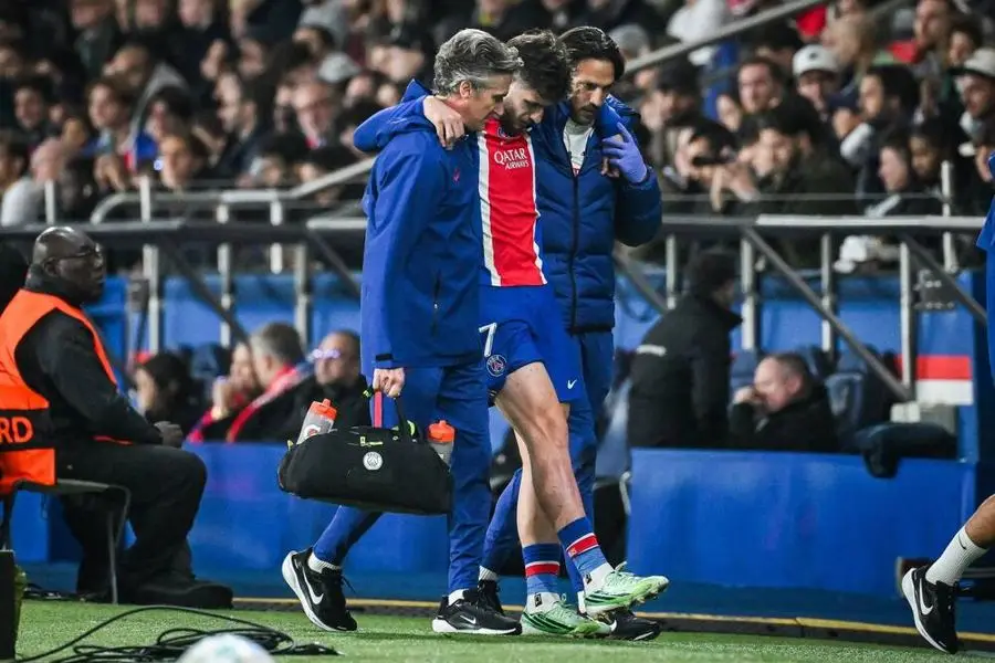 Khvicha Kvaratskhelia, con la camiseta del PSG, sale de la cancha ayudado por dos integrantes del cuerpo técnico. Foto: La Nación