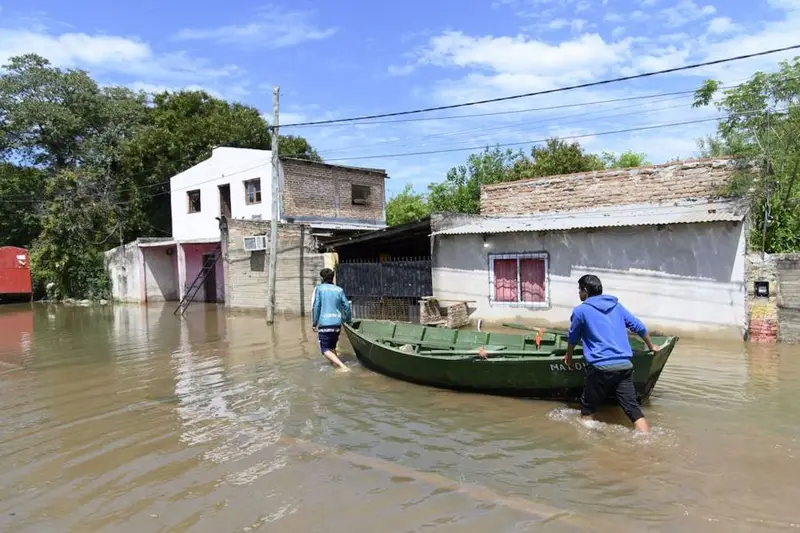 Dos vecinos cruzan el agua con una lancha en una calle inundada del litoral. Foto: LA NACION