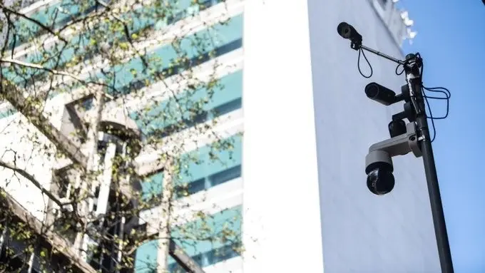 Cámaras montadas en un poste, frente a un edificio de vidrio. Foto: Montevideo Portal