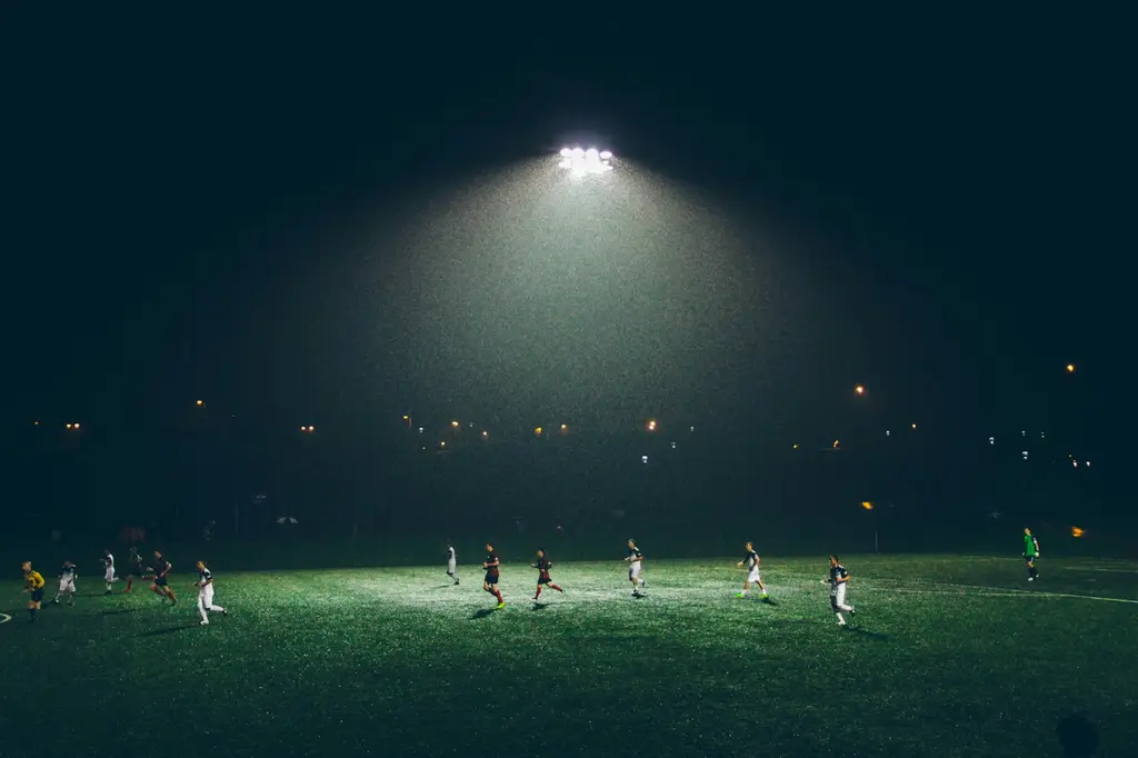Un partido de fútbol de noche, bajo los reflectores. Foto: Unsplash
