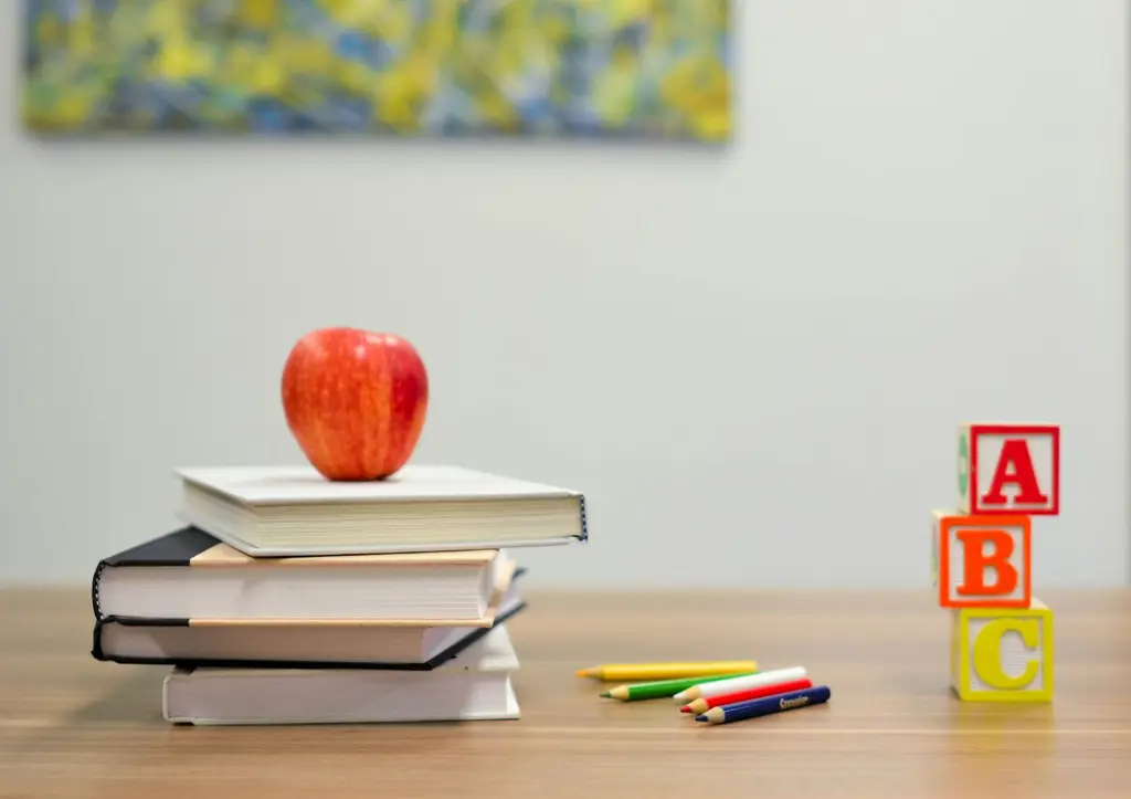 Libros, una manzana y bloques con letras sobre una mesa. Foto: Unsplash