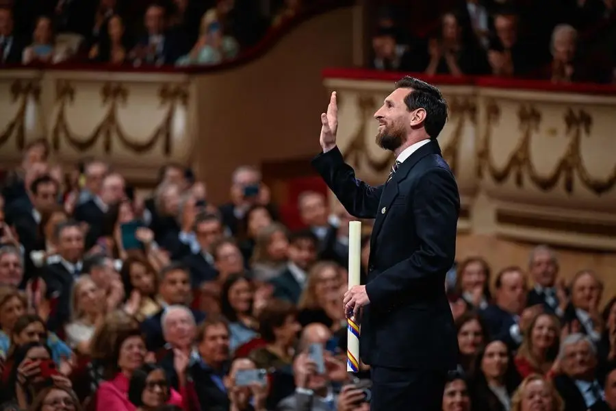 Lionel Messi, de traje oscuro, saluda en el escenario del teatro Campoamor con el premio en la mano. Foto: La Nación