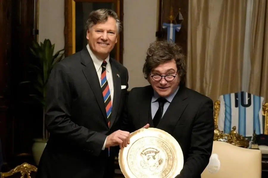 Christopher Landau y Javier Milei sostienen un sello dorado en un despacho, con una camiseta argentina detrás. Foto: La Nación
