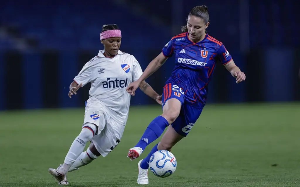 Una jugadora de Nacional, de blanco, disputa la pelota con una de Universidad de Chile. Foto: El País