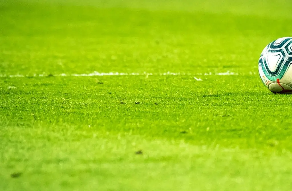 Cancha de fútbol iluminada de noche. Foto: Unsplash