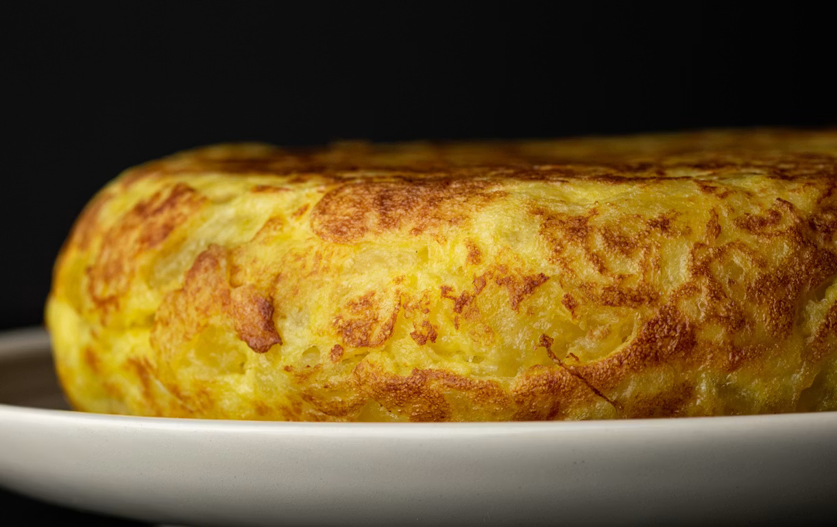 Tortilla de papas presentada en un plato, destacando su textura dorada. Foto: El País