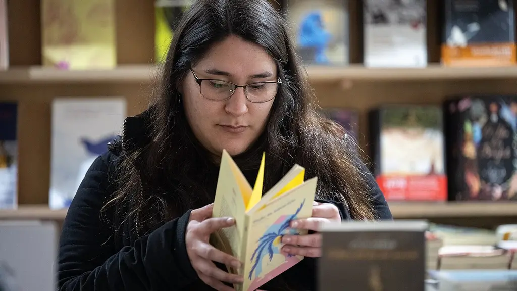 Una visitante hojea un libro entre estanterías en una edición anterior de la Feria Internacional del Libro de Montevideo. Foto: Santiago Mazzarovich / Wikimedia Commons (CC BY-SA 4.0) (archivo)