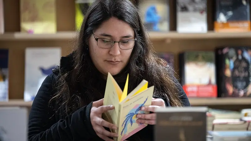 Una visitante hojea un libro entre estanterías en una edición anterior de la Feria Internacional del Libro de Montevideo. Foto: Santiago Mazzarovich / Wikimedia Commons (CC BY-SA 4.0) (archivo)