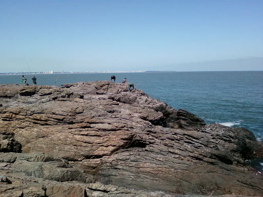 Pescadores sobre las rocas de Punta Ballena, con los edificios de Punta del Este al fondo; la zona busca ingresar al Sistema Nacional de Áreas Protegidas. Foto: Cleant / Wikimedia Commons (CC BY 3.0) (archivo)