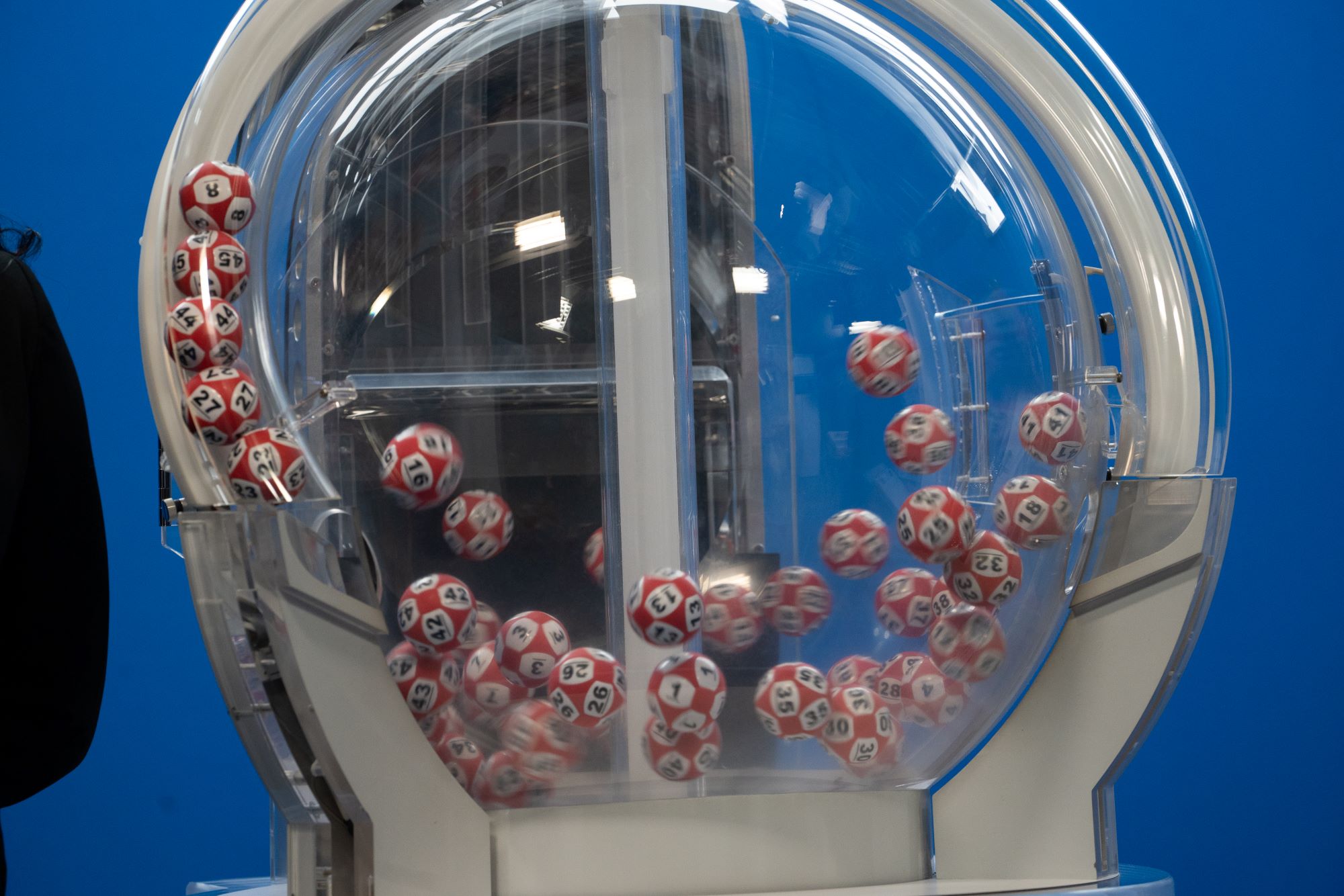 Boleto de lotería con números y máquina de sorteos. Foto: Clarín