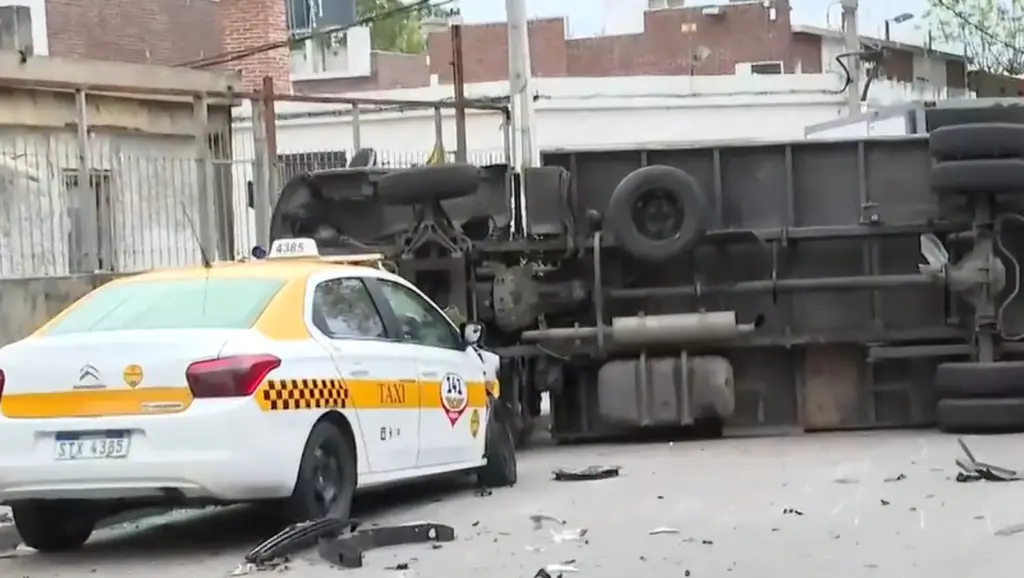 Un taxi blanco y amarillo junto a un camión volcado. Foto: Montevideo Portal