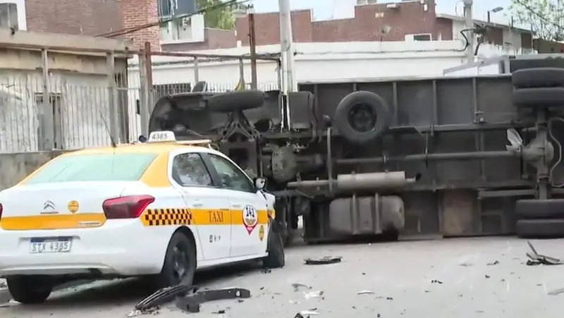 Un taxi blanco y amarillo junto a un camión volcado. Foto: Montevideo Portal